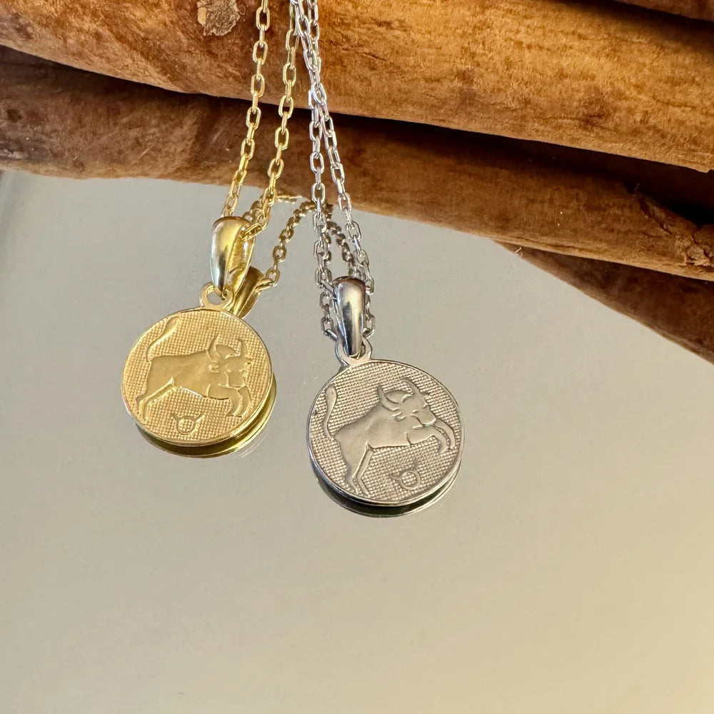 Gold and silver zodiac pendants featuring a bull design, perfect for men or women seeking a classic astrological style.