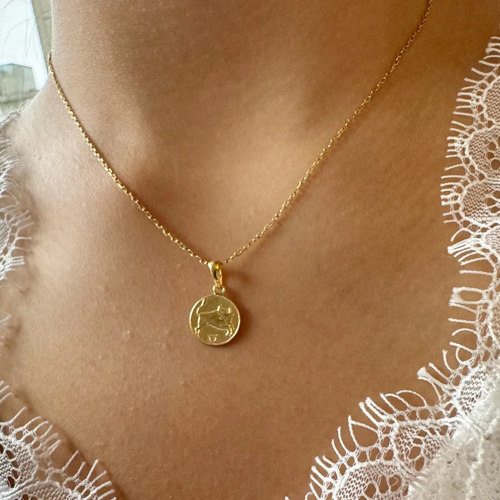 Gold zodiac coin necklace on a delicate chain, perfect for women seeking minimalist style for daily wear.