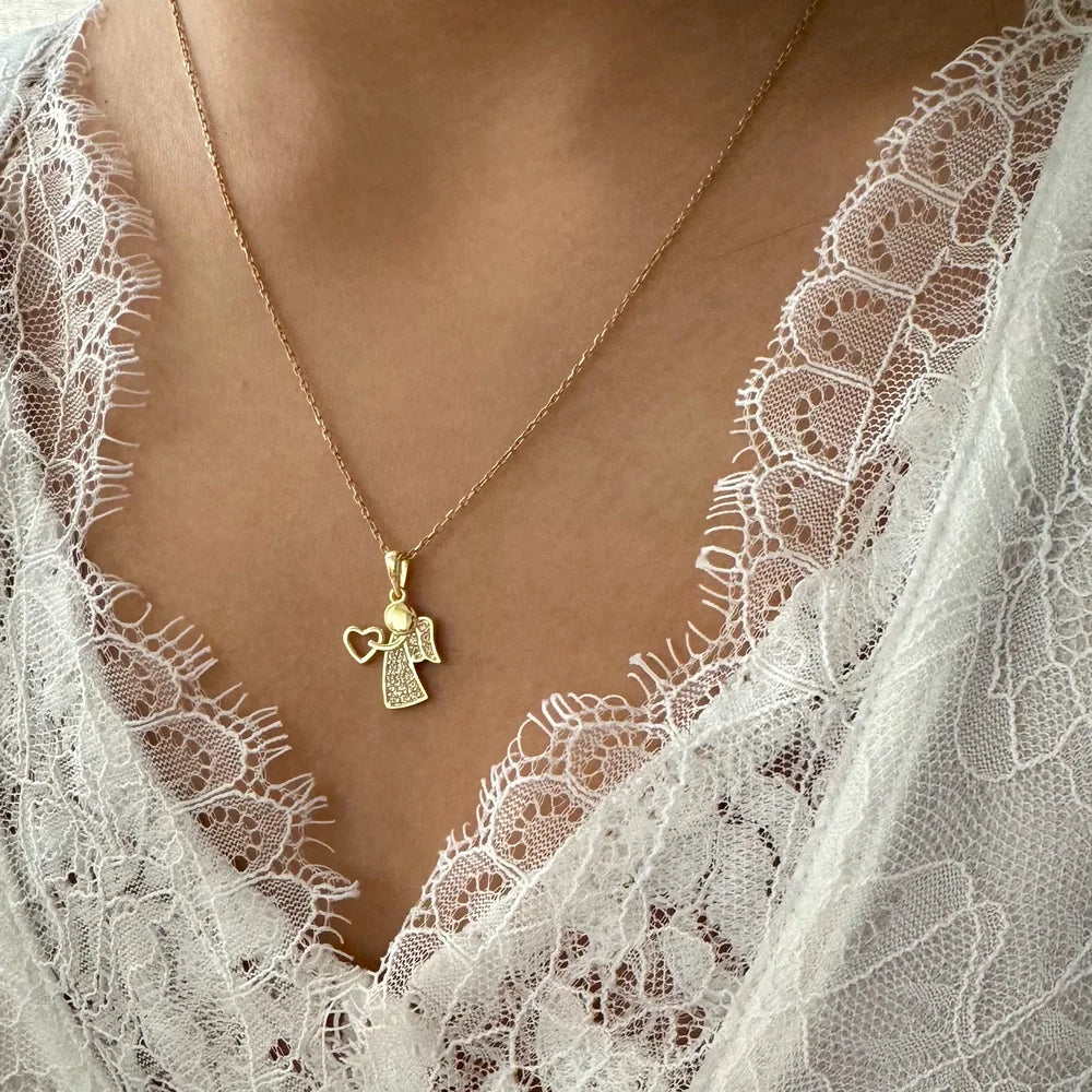 Delicate gold angel pendant necklace with heart charm, perfect for women looking for a minimalist, meaningful accessory.