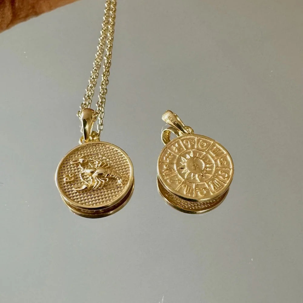Gold zodiac pendant necklace featuring intricate crab and astrological designs, perfect for women’s chic, bohemian style.
