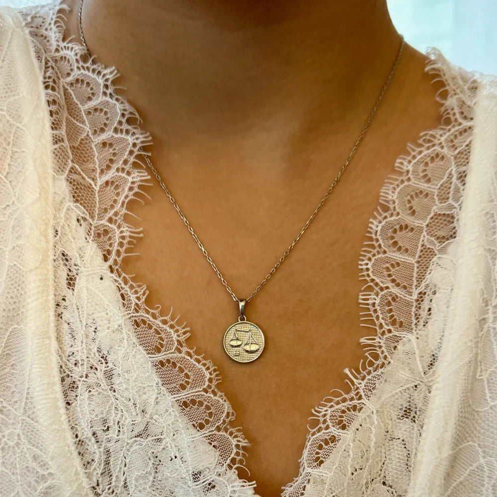 Gold balance scale pendant necklace, perfect for women seeking a minimalist or classic style for any occasion.