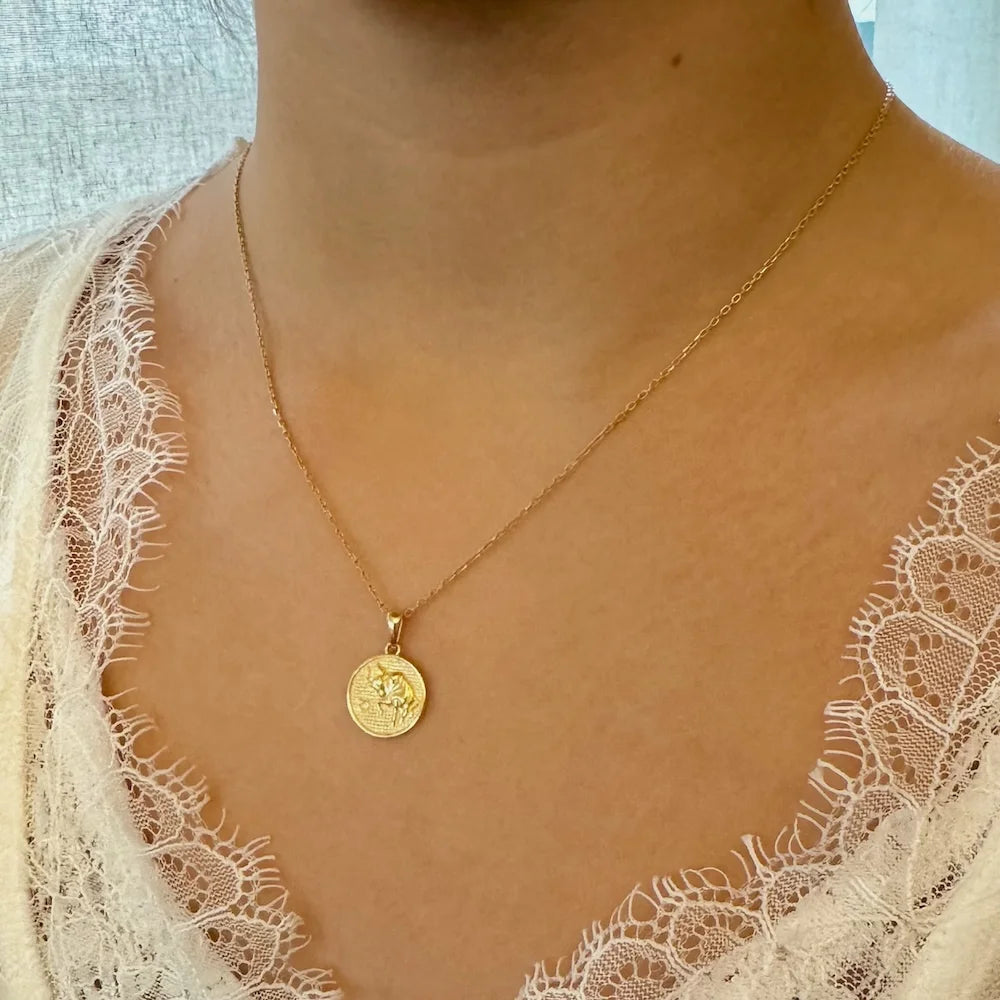 Gold coin pendant necklace on a woman, perfect for a minimalist style or casual outfits. Ideal for everyday wear.
