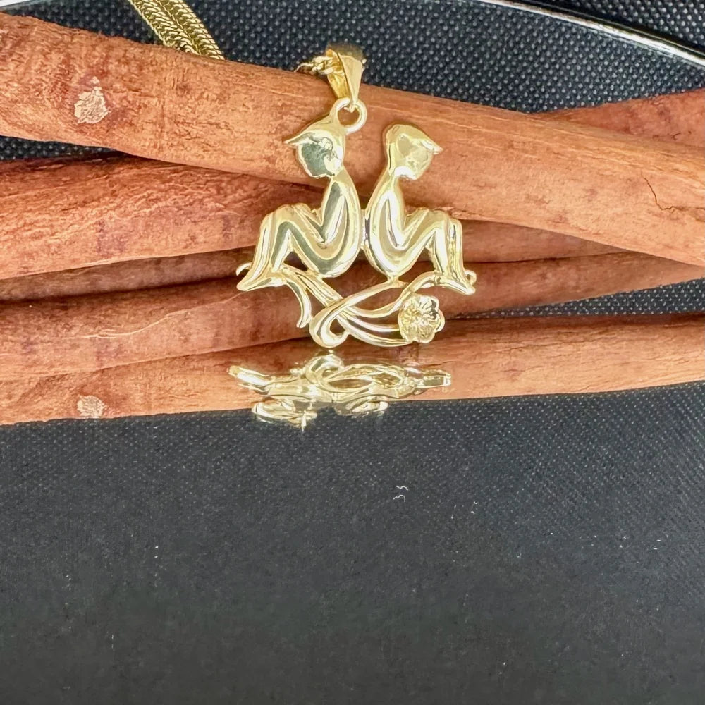 Gold pendant featuring two figures sitting on a flower vine, perfect for women embracing a unique, playful style.