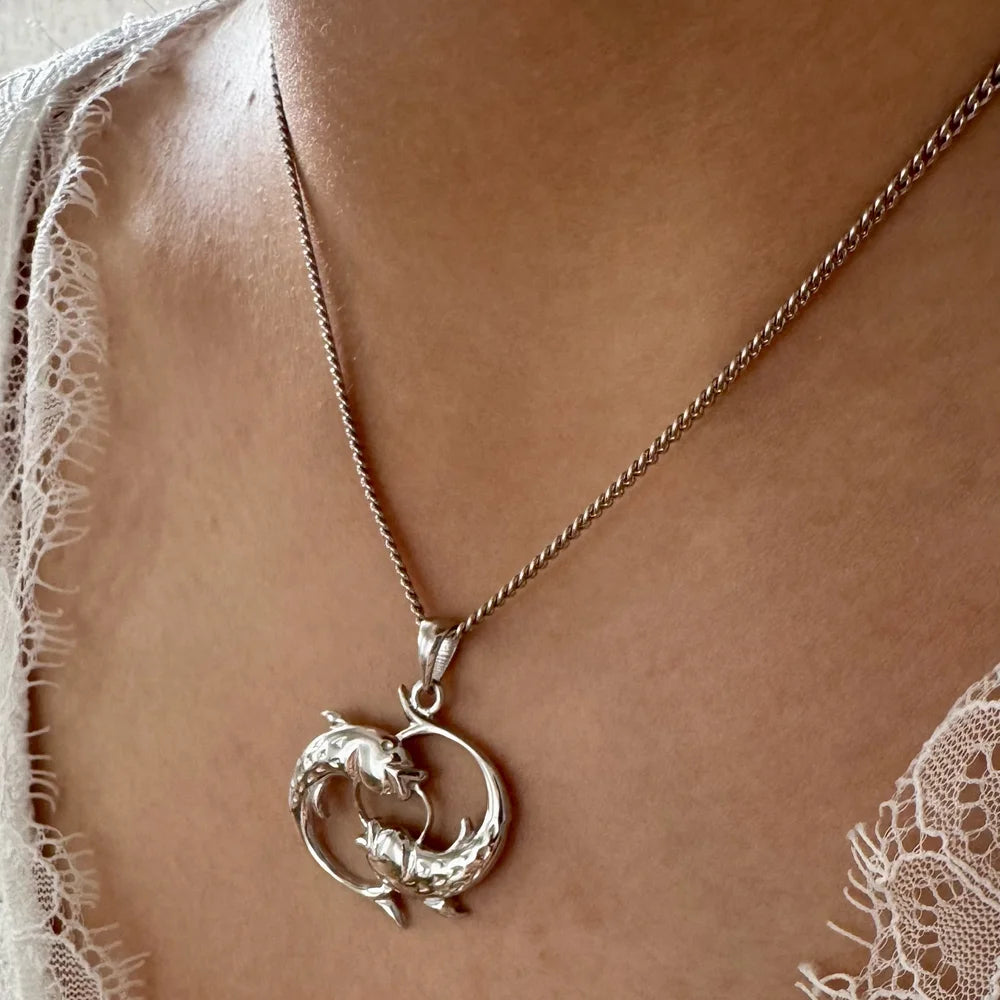 Silver dolphin pendant necklace, perfect for women seeking a unique, ocean-inspired jewelry piece. Ideal for casual wear.