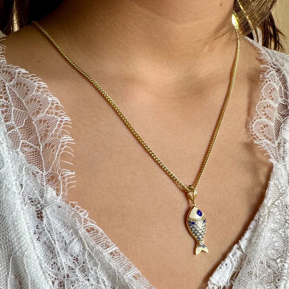 Gold fish pendant necklace adorned with blue gemstones, perfect for women seeking a whimsical, bohemian accessory.
